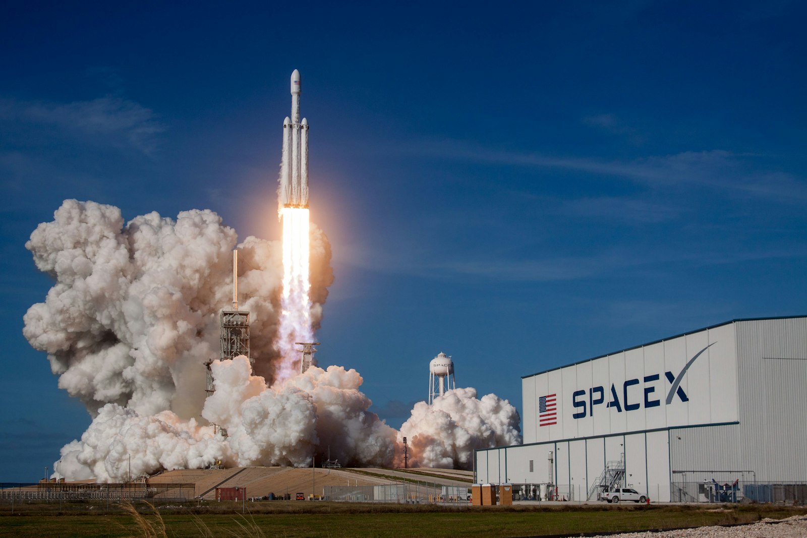 Heavy-lift rocket lifting off beside the launch hangar.